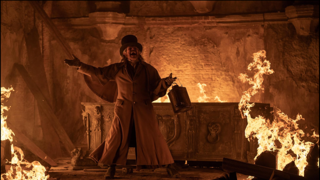 An intense scene from Nosferatu (2024), featuring Willem Dafoe as Professor Bulwer surrounded by flames, passionately delivering a critical moment in the gothic horror narrative.